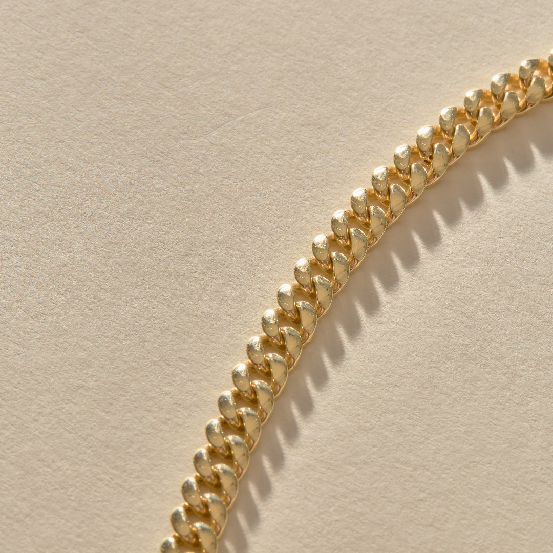 Gold chain bracelet on a beige background